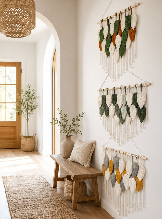 Three bohemian leaf macrame wall hangings displayed on a white wall in a bright, modern entryway.