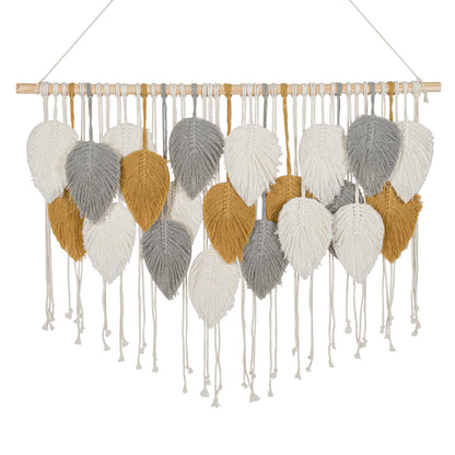 A hand-knotted macramé wall hanging featuring woven leaf shapes in white, silver and gold, suspended from a light wood dowel with a hanging string.
